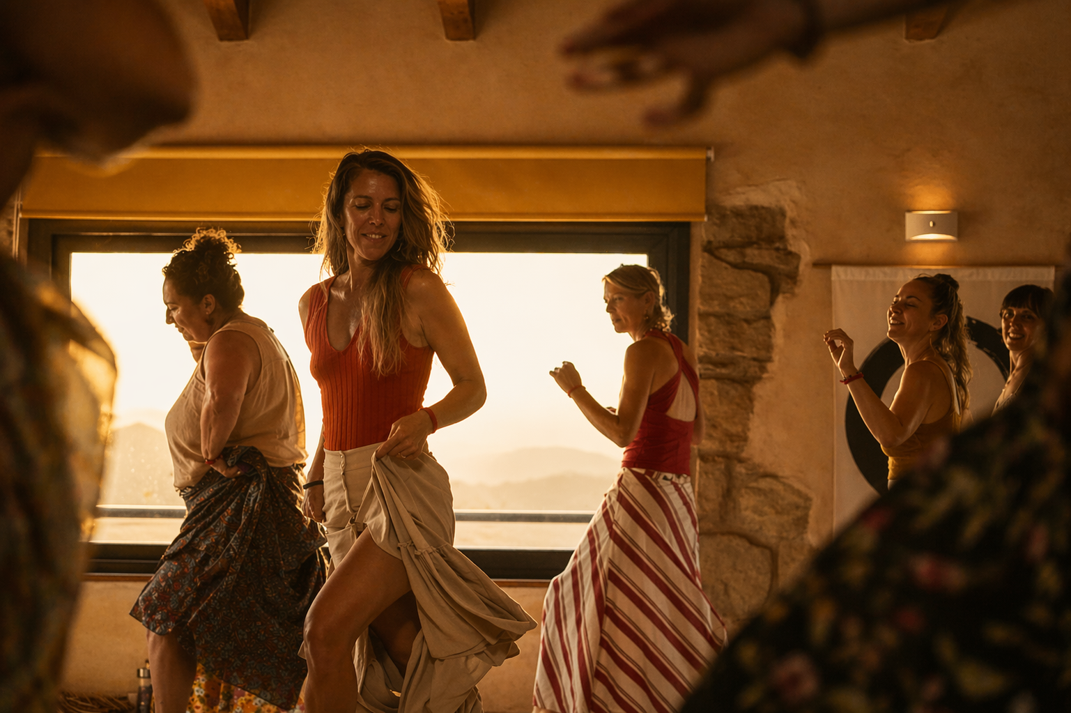Mujeres danzando frente a una ventana al atardecer